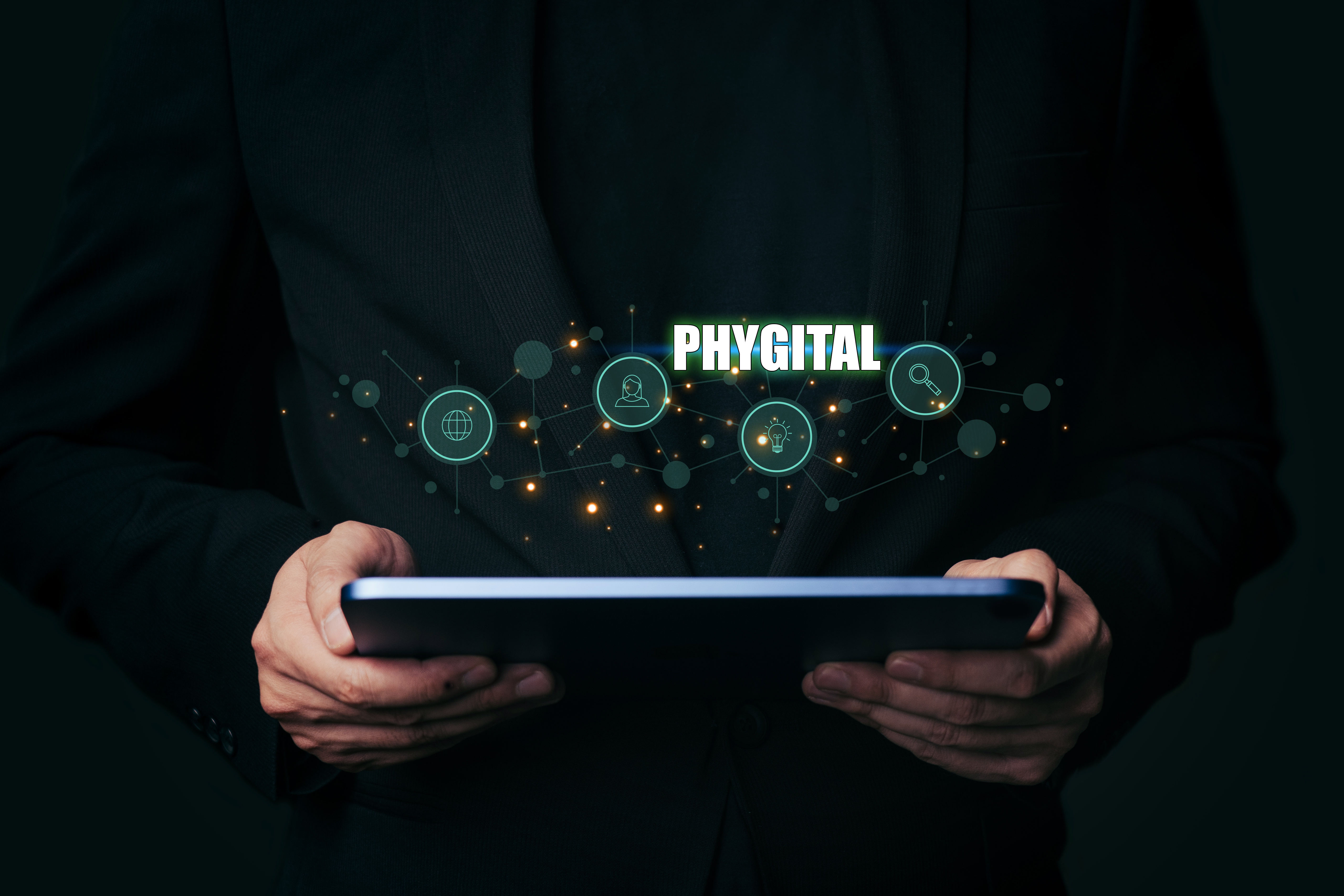A person holding a tablet with a glowing phygital network of connected icons above it